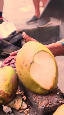 Kadın taze içecek için pala ile hindistan cevizi kesiyor.