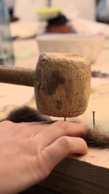 Kürk hazırlamak için tahta çekiçle küçük hayvan postlarını masaya çivilemek.