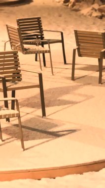 Şehir parkındaki park sandalyeleri karla kaplıydı. Açık havada kış manzarası yaratıyordu.