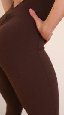 Kahverengi spor giyim kuşamında kaslı kalça ve bacakların yavaşça çömelmesi.