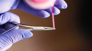 Doktorun mor iple sarmaladığı ortodontik elastik zincir. Yüksek kalite 4k görüntü