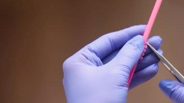 Bağları bağlamak için klemp kullanan ortodontist, kesin ortodonti iş teli hazırlama tekniğini ve profesyonel diş tedavisi sürecini gösterir.