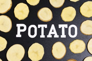 Dilimlenmiş taze patates. Karanlık bir yüzeyde yatıyor..