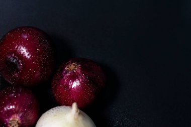 Ekranın sol alt köşesinde bir grup taze kırmızı-mor ve beyaz soğan başları. Sağ yarısı boş. Koyu arkaplan.