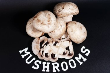 Bir demet beyaz şampiyon. Bazıları dilimlere ayrılmış. MUSHROOMS 'un altındaki yazıt bir yay şeklindedir. Yukarıdan görünüşü.