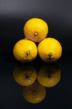Koyu bir yüzeyde sarı limonlar. Görüntünün yansıması.