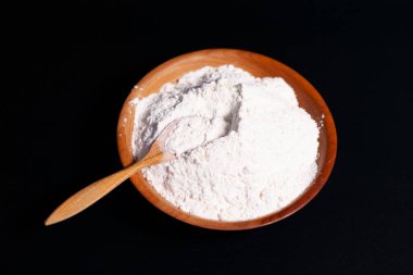 Ekranın ortasında üzerinde un yığını olan kahverengi bir kupa var. Tahta kaşık..