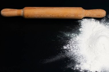 Sağda, masanın karanlık yüzeyinde bir beyaz un yığını var. Mutfağın üstünde merdane var..