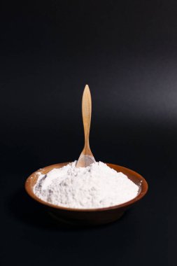 Ekranın ortasında üzerinde un yığını olan kahverengi bir kupa var. Tahta kaşık dik konumda..