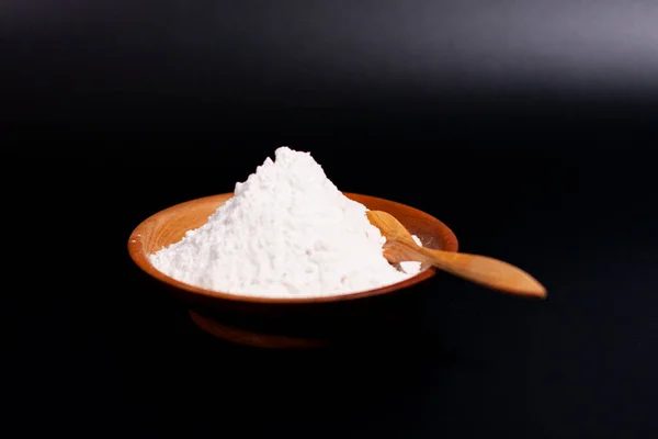 Un mucchio di farina di grano bianco in una tazza. Cucchiaio di legno. — Foto Stock