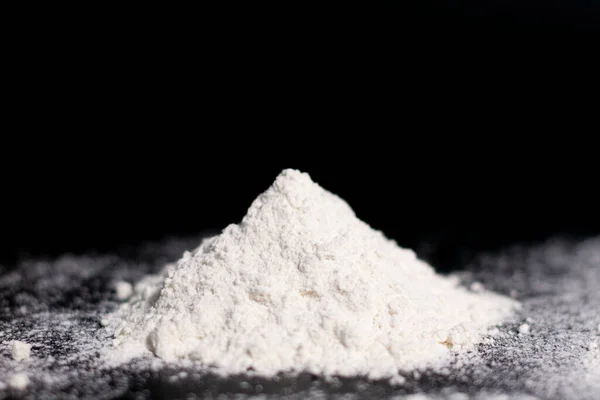 A mound of white flour on a dark surface. Side view. — Stock Photo, Image