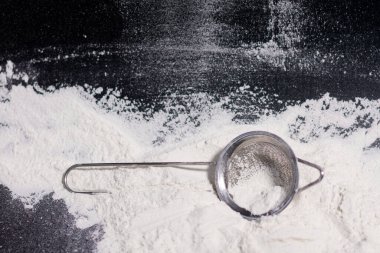 Un yığınının üzerinde sapı olan metal bir elek..