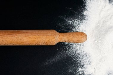 Sağda, masanın karanlık yüzeyinde bir beyaz un yığını var. Ortasında merdane var..