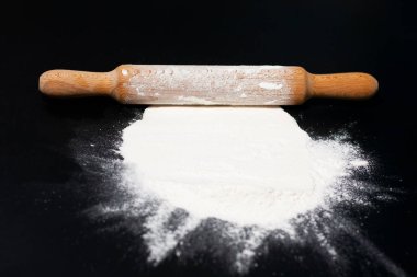 Masanın üzerinde ekranın ortasında beyaz undan bir tepe var. Mutfağın üstünde merdane var..