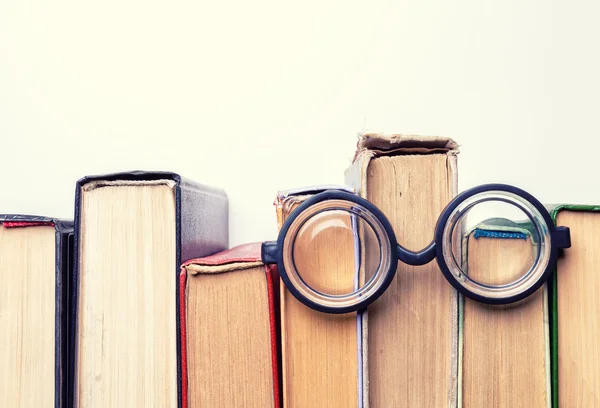 Schwarze runde Gläser lagen auf einem Stapel ramponierter alter Bücher.. — Stockfoto