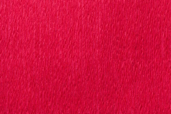 Textural bright red background of wavy corrugated paper, close-up.