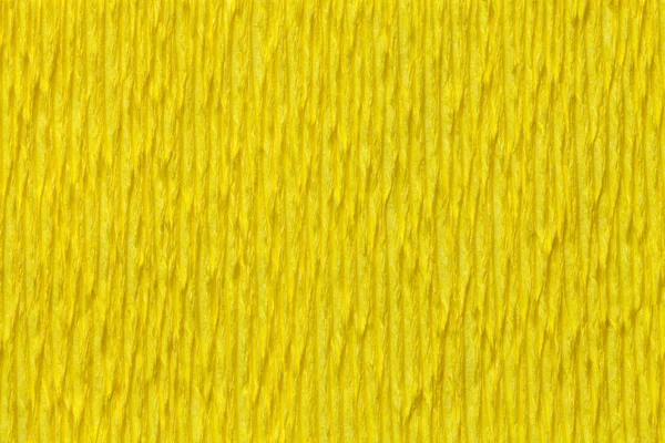 Textural yellow background of wavy corrugated paper, close-up.