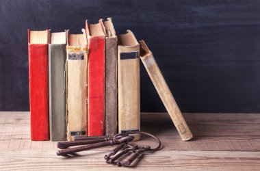 Eski vintage kitap yığını ve eski büyük demir anahtarları bir sürü ahşap bir masaya yalan.