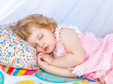 Küçük kıvırcık kız pembe pijama yumuşak yatak kapalı gözler ile uyku.