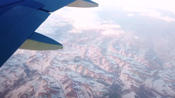 Repülőgép repül a felhők között havas sapkás hegyek felett. — Stock videók