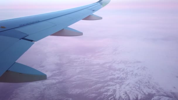 Karlı dağların üzerinde bulutların arasında uçan uçak.. — Stok video