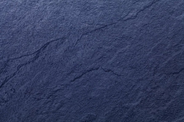 Navy blue background of natural slate. Texture of stone closeup. Graphite backdrop macro