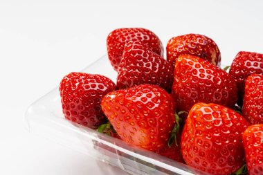 Fresh strawberries packed in a plastic container on white background