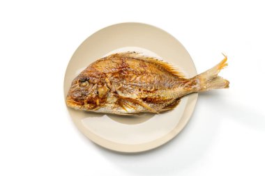Grilled whole sea bream served on a plate on white background