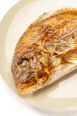 Grilled whole sea bream served on a plate on white background
