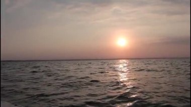 Güzel bir gün batımı ya da okyanusun üzerinde gün doğumu Parlak güneş puslu bir gökyüzünde sarkıyor nazikçe hareket eden deniz dalgalarına uzun altın ve turuncu bir yansıma