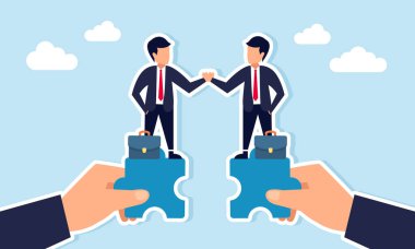 Yapboz parçasının üzerinde duran iki işadamı el sıkışarak iş birliği anlaşmasını resmediyor.