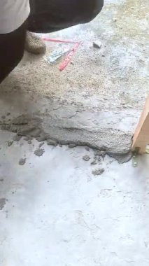 İnşaat işçisi inşaat alanında çimento harcı ile beton bloklar döşüyordu. Duvarcılık sırasında güneş ışığı altında ellerin yakın çekimleri, doku ve inşa sürecini gösterir.