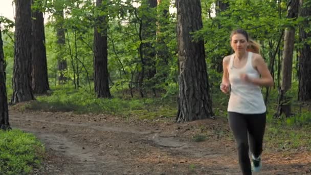 Młoda kobieta działa rano w lesie, w zwolnionym tempie — Wideo stockowe