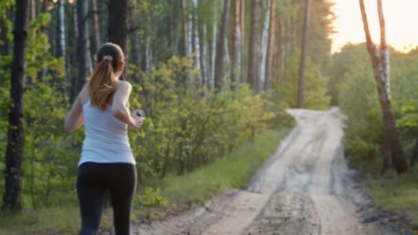 Jonge vrouw die in de ochtend in het bos loopt — Stockvideo