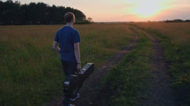 Genç adam yürümeye gitar, ağır çekim