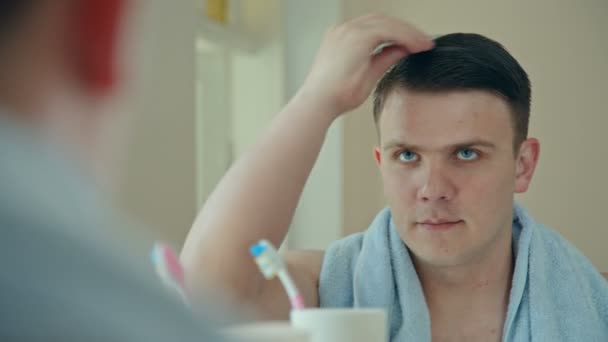 El hombre arregla su cabello delante del espejo — Vídeos de Stock