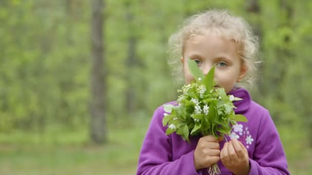 Menina cheirando uma flor de margarida no prado — Vídeo de Stock