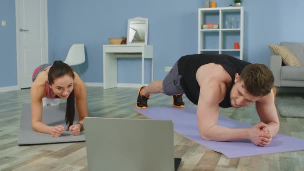 Jong paar staan in Plank kijken naar training video — Stockvideo