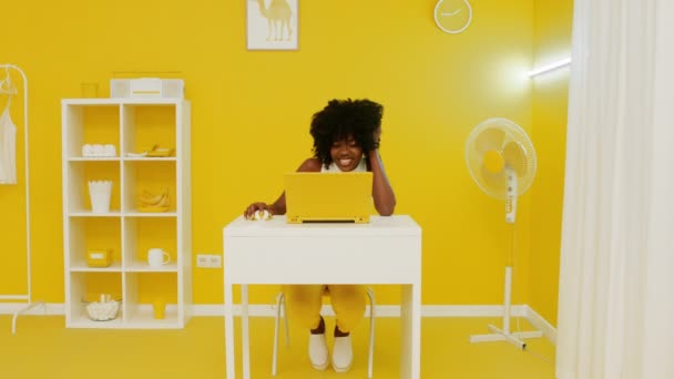 Черная женщина сидит за рабочим столом и танцует — стоковое видео