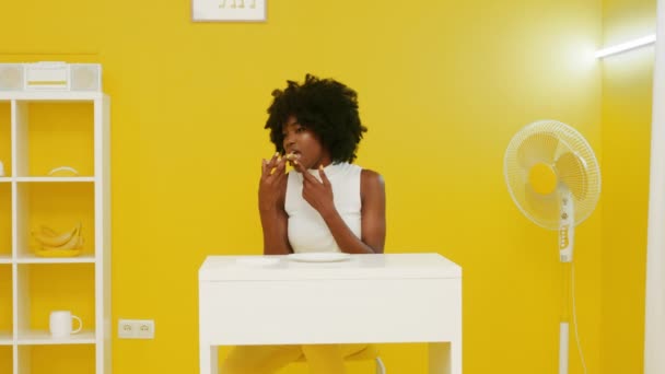 Kobieta je pizzę w żółto-białym pokoju. — Wideo stockowe