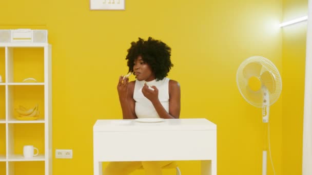 Czarna kobieta je smaczną pizzę w żółtym pokoju — Wideo stockowe