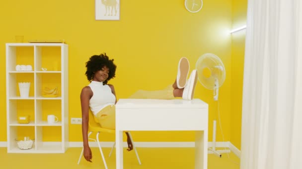 アフリカ人女性が黄色のオフィスでリラックスしているカメラを見て — ストック動画