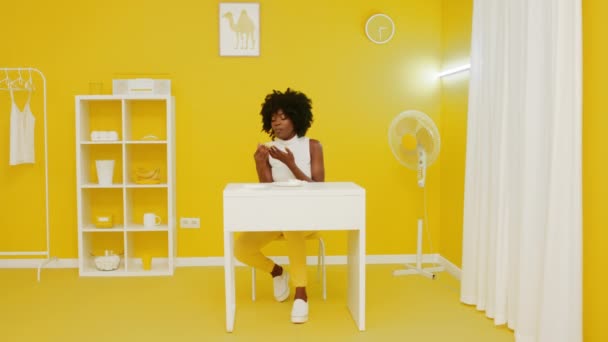 Kobieta je fast food w żółtym pokoju — Wideo stockowe