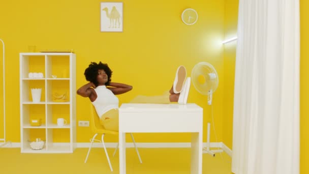 Afrykańska kobieta relaksuje się w żółtym wnętrzu — Wideo stockowe