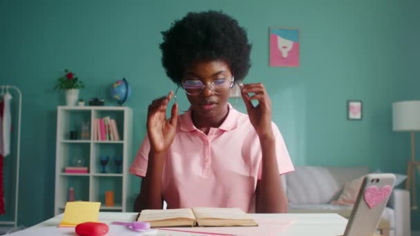 Mujer está leyendo un libro y mira a la cámara — Vídeos de Stock