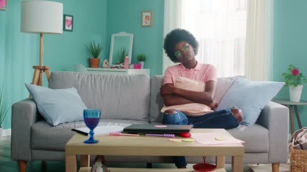 Mujer afroamericana aburrida está sentada en un sofá — Vídeos de Stock