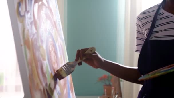 Zwarte vrouw kunstenaar schildert symbolische zon — Stockvideo