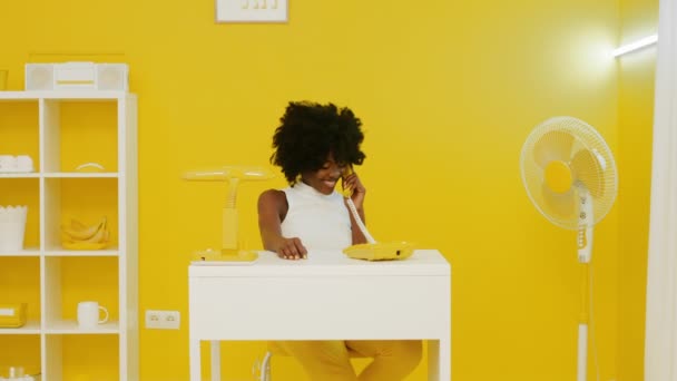 Ładna kobieta cieszy się rozmową telefoniczną w żółtym biurze — Wideo stockowe