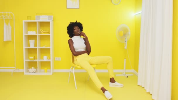 Portrét černošky sedící na žluté židli — Stock video