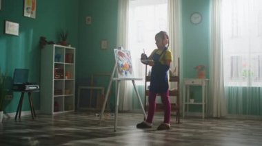 Önlüklü Küçük Kız Resim Yapıyor ve Müzik Dinliyor